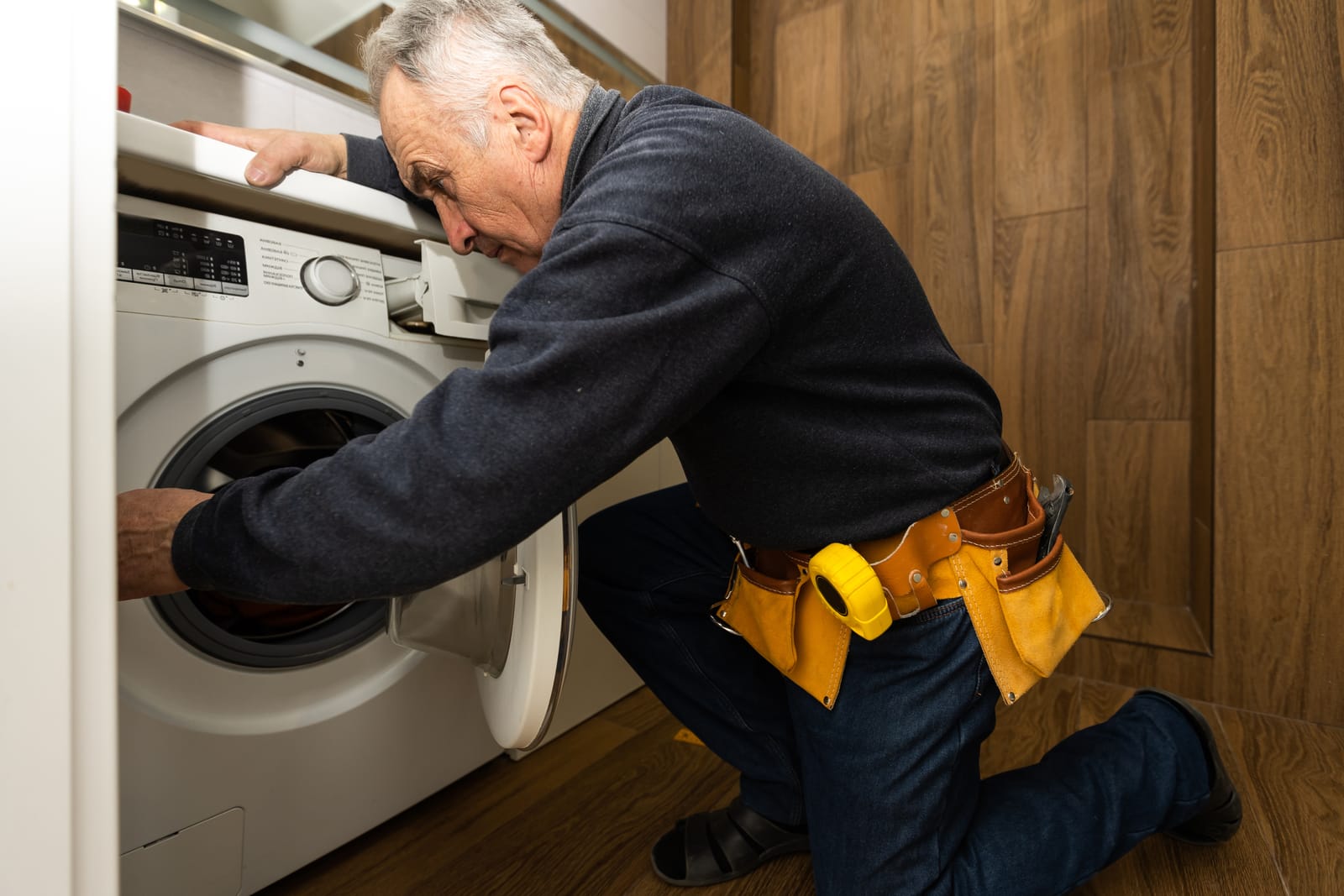 A professional technician working on a washing machine repaired to restore its performance in a UK home.