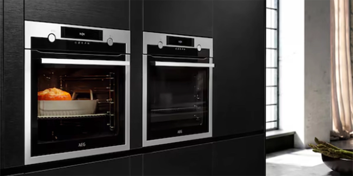 A professional local engineer performing an Electric Oven Repair Service on a built-in stainless steel oven in a modern kitchen.