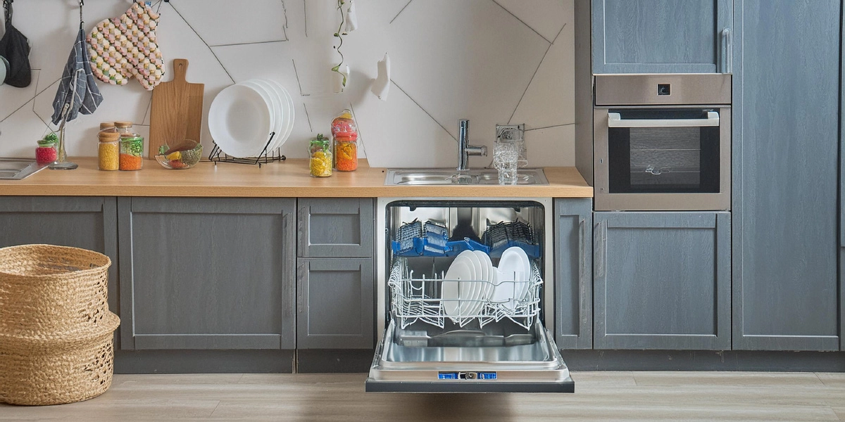 A professional appliance engineer performing dishwasher repairs in a family kitchen, fixing a drainage issue to restore the appliance to full working order.