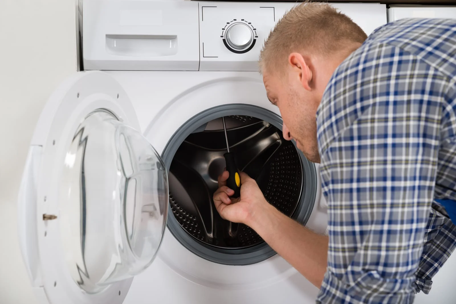 A technician inspecting a noisy washing machine to check for worn washing machine drum bearings and apply a washing machine vibration fix