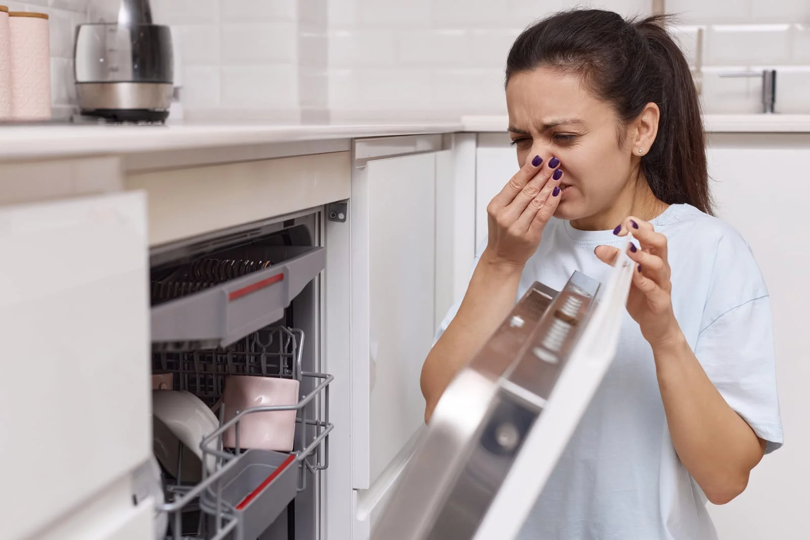 55799508_woman-smells-terrible-smell-coming-from-dishwasher-machine - Appliance Repair Men - Appliance Repair Men Dishwasher Smells