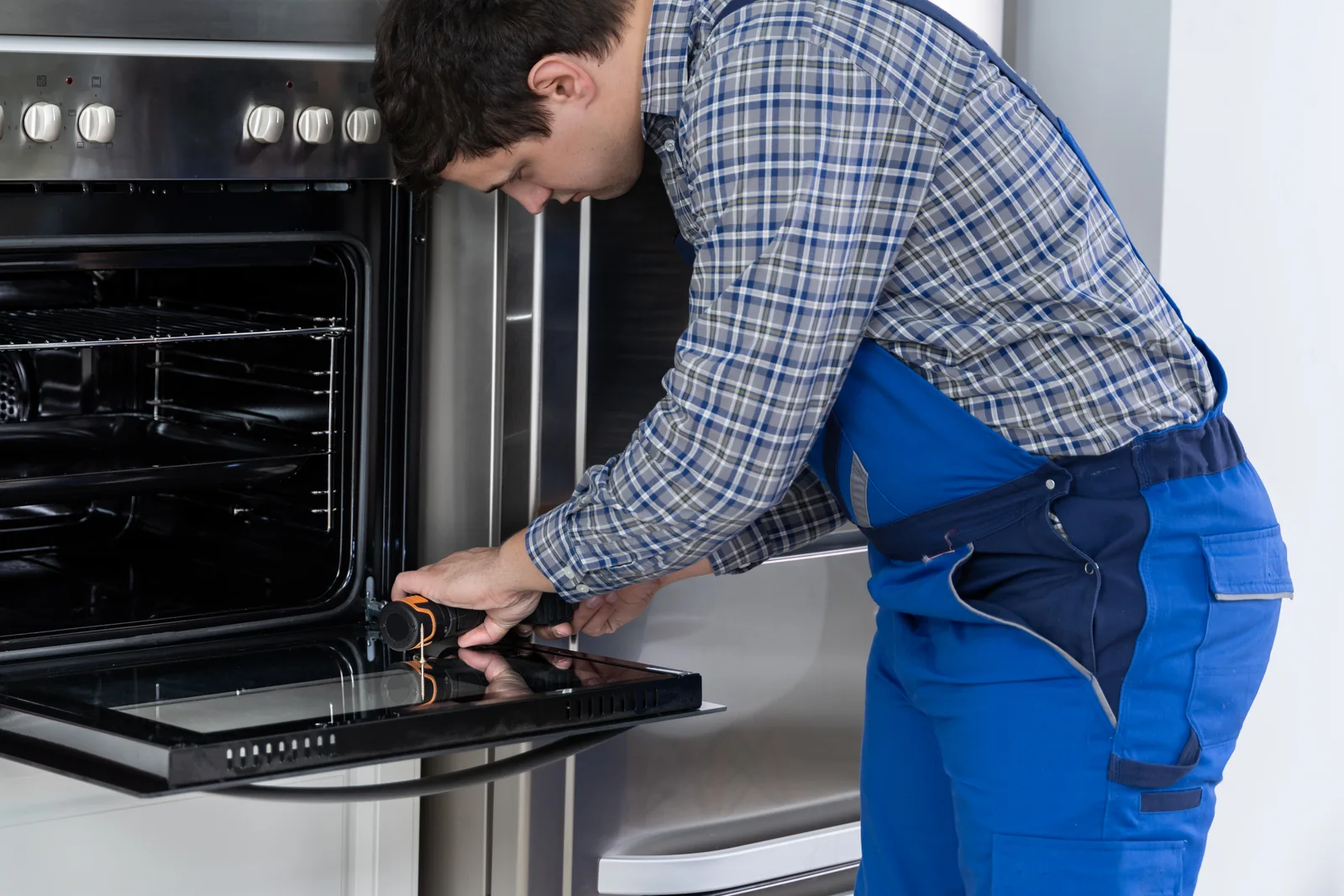 Integrated Oven Tripping the Electrics and How We Trace the Fault - Appliance Repair Men - Appliance Repair Men Engineer easing a built-in oven out of its cabinet to test wiring after an integrated oven tripping fault in an Aughton kitchen