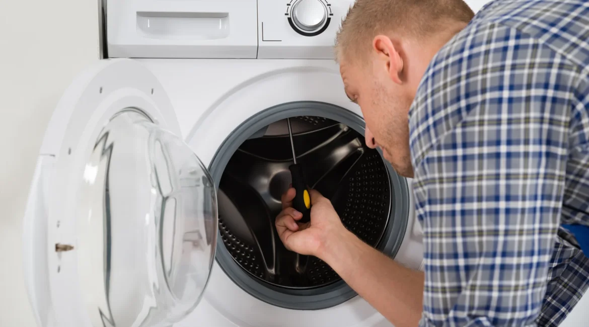 Engineer turning the drum by hand to check a washing machine drum stuck fault on a front loader in a UK utility room